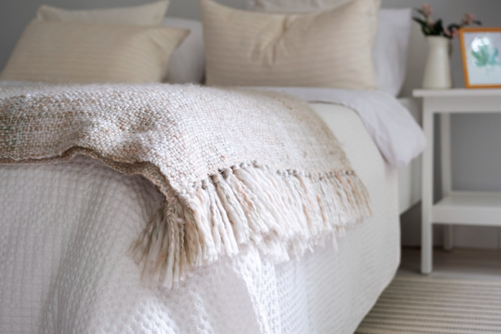 Neutral toned bed with assortment of knit throw blankets Neutral toned bed with assortment of knit throw blankets