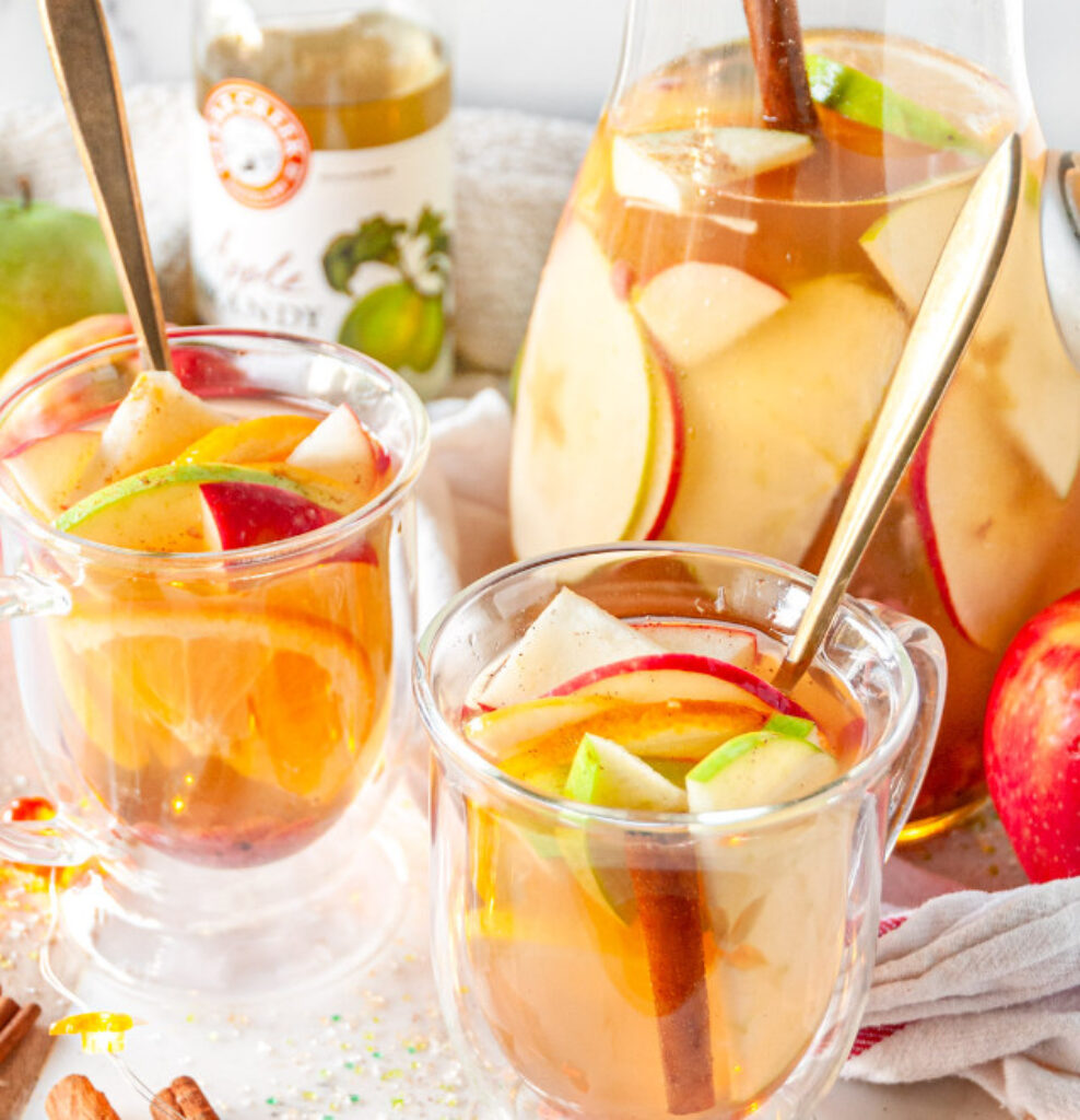 Warm spiced apple cider sangria in mugs with apple slices
